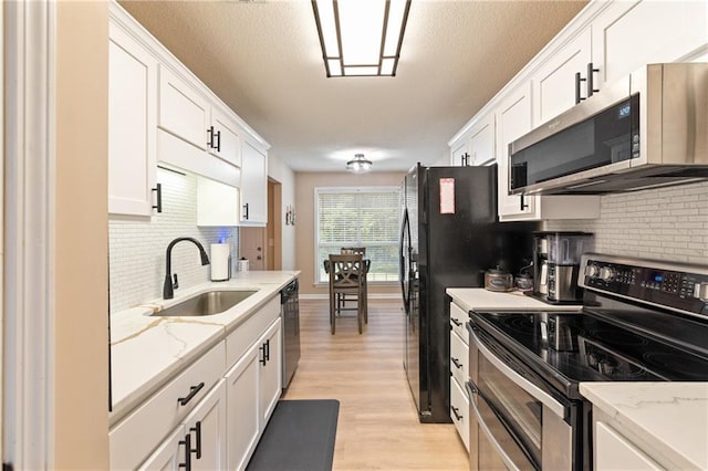 15 Fairwoods Ct, Covington, GA 30016 - kitchen with appliances with stainless steel finishes, tasteful backsplash, white cabinets, light wood-style flooring, and a textured ceiling