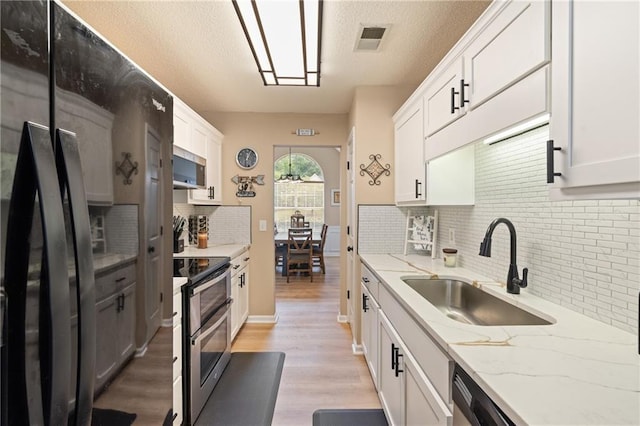 15 Fairwoods Ct, Covington, GA 30016 - kitchen featuring appliances with stainless steel finishes, backsplash, light wood finished floors, light stone countertops, and white cabinetry