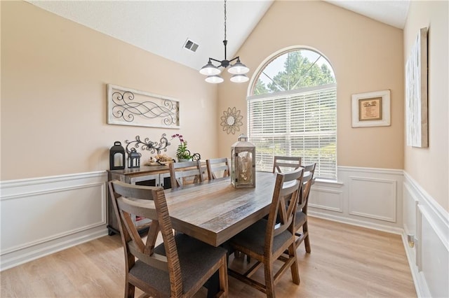 15 Fairwoods Ct, Covington, GA 30016 - dining area with a wainscoted wall, a chandelier, light wood finished floors, a decorative wall, and vaulted ceiling