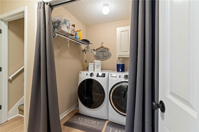15 Fairwoods Ct, Covington, GA 30016 - washroom featuring washing machine and clothes dryer, light wood finished floors, a textured ceiling, and cabinet space
