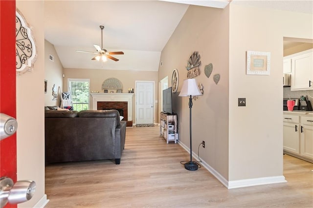 15 Fairwoods Ct, Covington, GA 30016 - living room featuring a ceiling fan, light wood finished floors, vaulted ceiling, and a brick fireplace