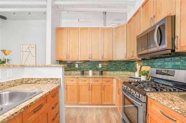 572 Edgewood Ave SE Unit # 106, Atlanta, GA 30312 - kitchen with decorative backsplash, appliances with stainless steel finishes, light stone countertops, and light wood-style flooring