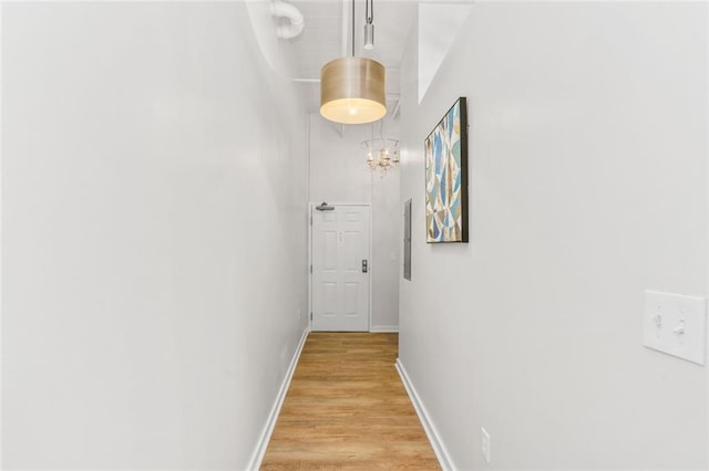 572 Edgewood Ave SE Unit # 106, Atlanta, GA 30312 - hallway with light wood-type flooring, a high ceiling, baseboards, and an inviting chandelier