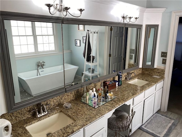 bathroom with an inviting chandelier, vanity, and a bath