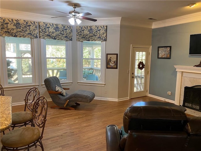 interior space featuring ceiling fan, ornamental molding, a high end fireplace, and hardwood / wood-style floors