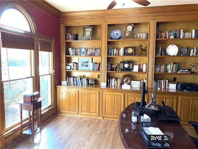 office space with ornamental molding, built in features, ceiling fan, and light hardwood / wood-style floors