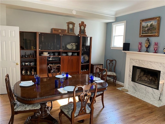 dining space featuring hardwood / wood-style floors, crown molding, and a premium fireplace