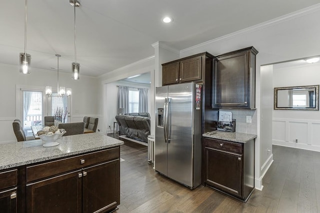 kitchen with pendant lighting, dark hardwood / wood-style flooring, stainless steel fridge, light stone counters, and dark brown cabinets