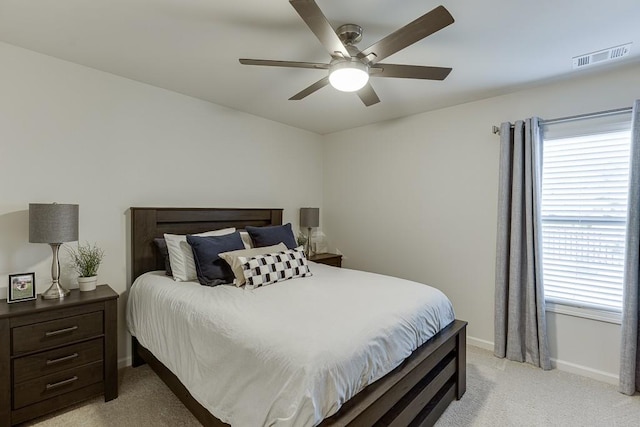 bedroom with ceiling fan, light colored carpet, and multiple windows