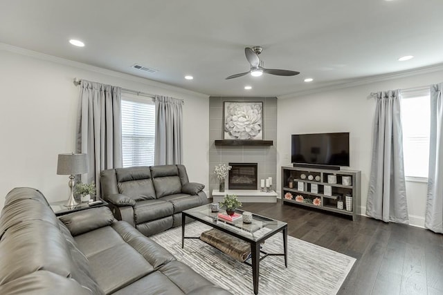 living room with a large fireplace, ceiling fan, crown molding, and dark hardwood / wood-style floors