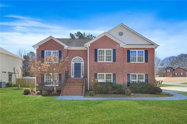 bi-level home featuring a front yard, central AC, and brick siding