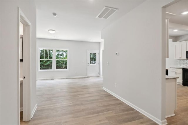 corridor featuring light wood-type flooring, baseboards, and recessed lighting