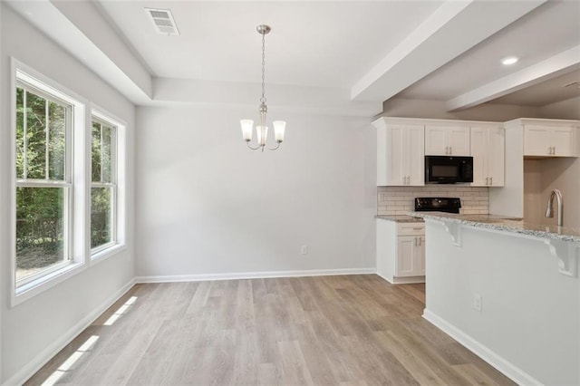 kitchen featuring black appliances, a breakfast bar area, plenty of natural light, and light wood-type flooring
