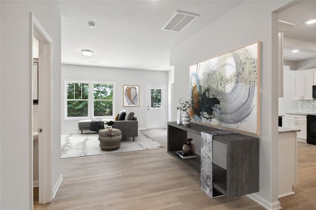 hall with light wood-style floors, baseboards, and recessed lighting
