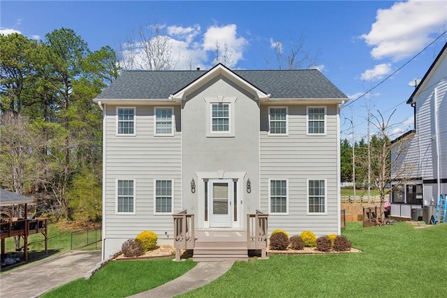 colonial-style house featuring a front lawn, cooling unit, and a shingled roof