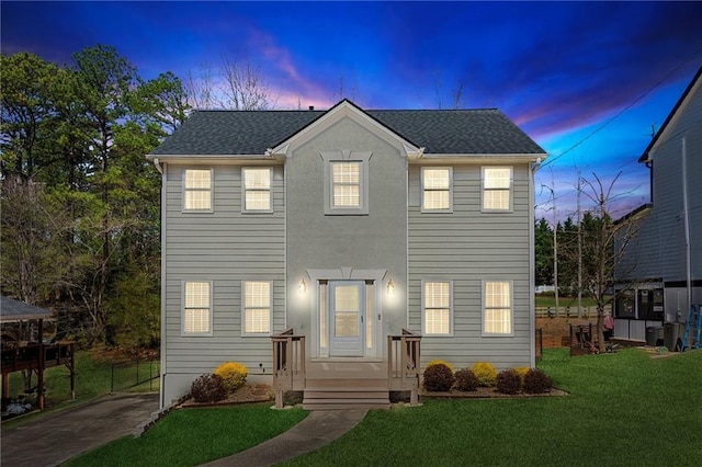 colonial home featuring a front yard, driveway, and a shingled roof