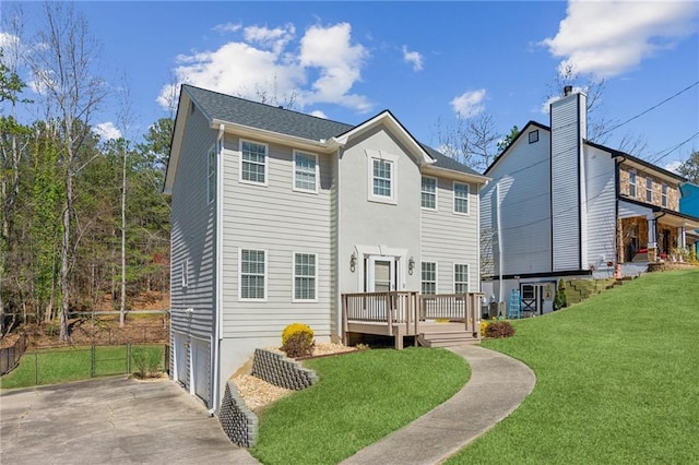 rear view of house featuring fence, driveway, a garage, a deck, and a lawn