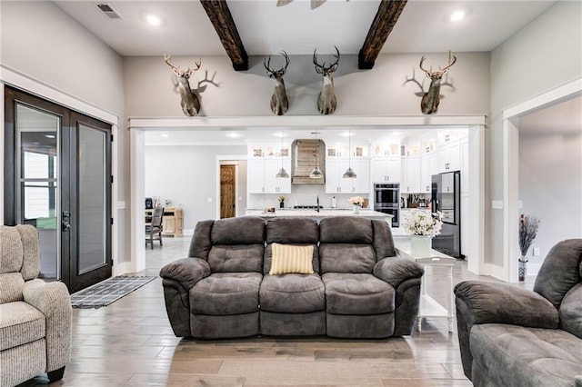 living room featuring beamed ceiling, french doors, and light hardwood / wood-style flooring