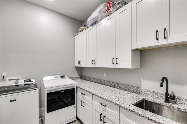 clothes washing area with sink, cabinets, and washer and dryer