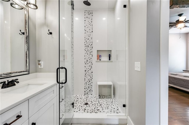 bathroom featuring vanity, hardwood / wood-style flooring, a shower with shower door, and ceiling fan