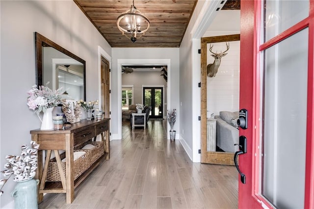 interior space with french doors, a notable chandelier, light wood-type flooring, and wooden ceiling