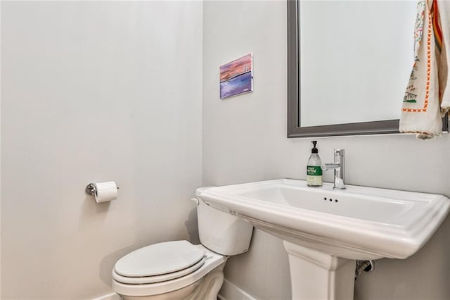 bathroom featuring toilet, baseboards, and a sink