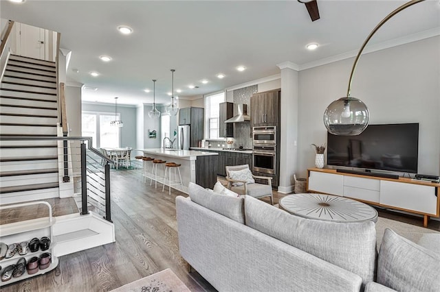 living room with stairway, recessed lighting, crown molding, and wood finished floors