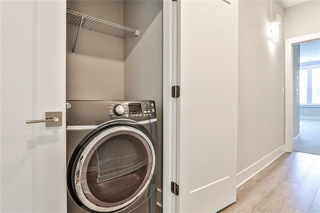 laundry area with baseboards, washer / dryer, wood finished floors, and laundry area