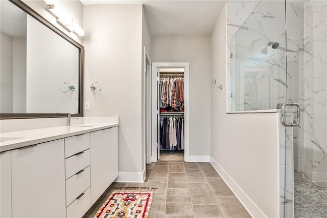 full bath with double vanity, a spacious closet, a marble finish shower, and a sink