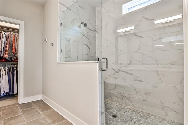 full bathroom with a marble finish shower, baseboards, and a walk in closet