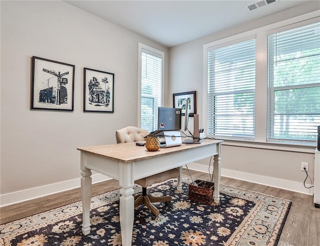 office with plenty of natural light, baseboards, visible vents, and wood finished floors