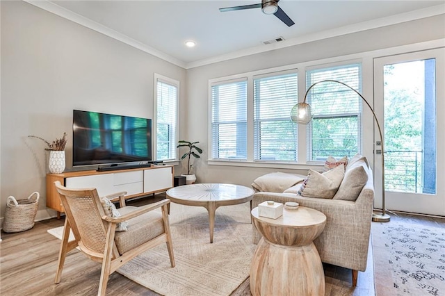 living room featuring plenty of natural light, wood finished floors, visible vents, and ornamental molding