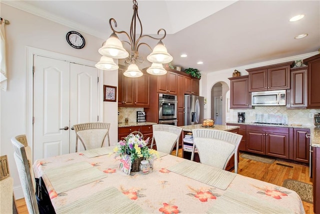 dining area featuring ornamental molding, an inviting chandelier, and light hardwood / wood-style flooring