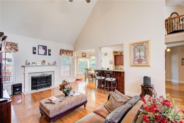 living room with light wood-type flooring, high vaulted ceiling, plenty of natural light, and ceiling fan