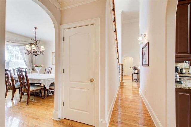 hallway with crown molding, a chandelier, and light hardwood / wood-style floors