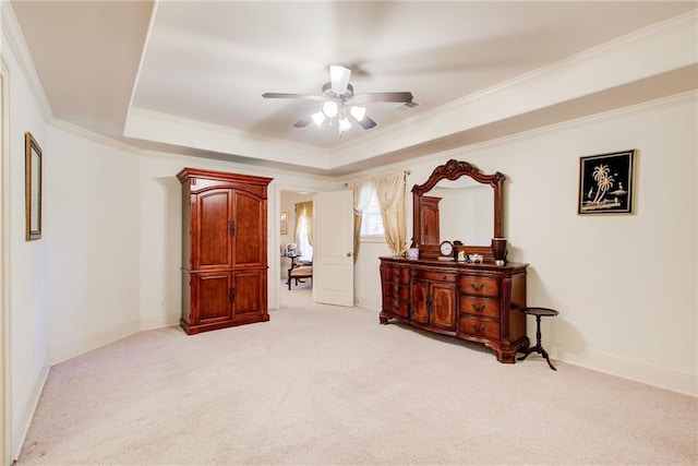 interior space with ornamental molding, light colored carpet, a tray ceiling, and ceiling fan