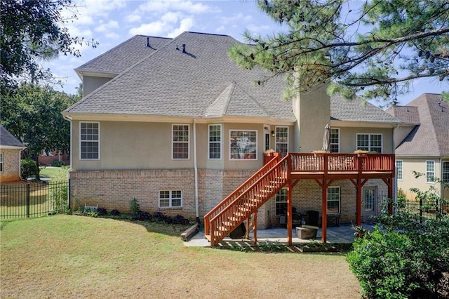 back of house featuring a yard, a wooden deck, and a patio