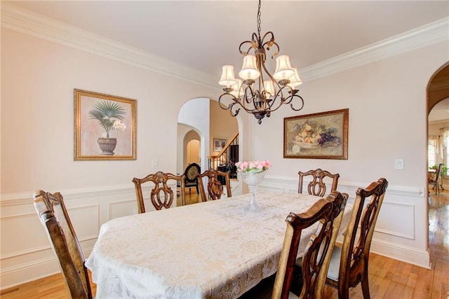 dining area with crown molding, a notable chandelier, and light hardwood / wood-style floors