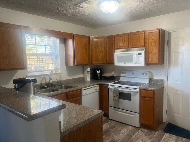 kitchen with white appliances, a textured ceiling, dark hardwood / wood-style flooring, sink, and kitchen peninsula