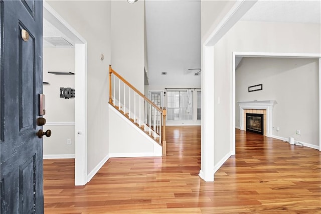 entryway featuring a tile fireplace, hardwood / wood-style floors, and a high ceiling