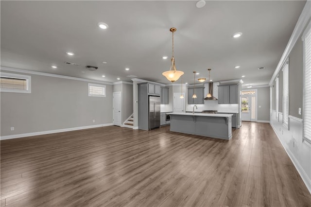 1179 Bennett Creek Overlook, Suwanee, GA 30024 - kitchen with gray cabinetry, stainless steel fridge, wall chimney range hood, open floor plan, and crown molding