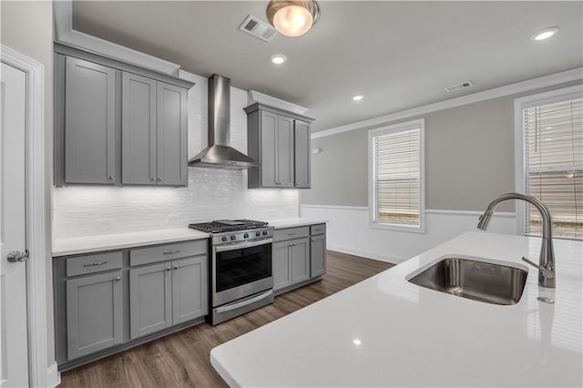 1179 Bennett Creek Overlook, Suwanee, GA 30024 - kitchen with gas stove, wall chimney range hood, gray cabinetry, a sink, and ornamental molding