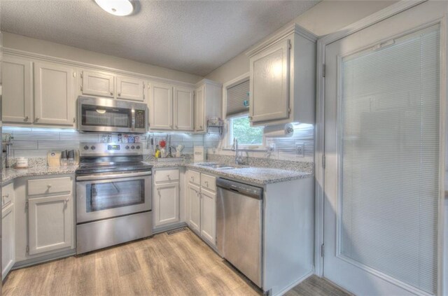80 Broadlands Dr, White, GA 30184 - kitchen featuring stainless steel appliances, light wood-style flooring, tasteful backsplash, a textured ceiling, and white cabinetry