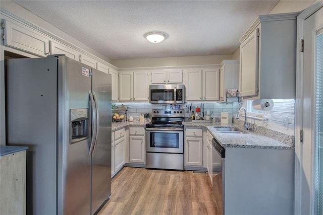 80 Broadlands Dr, White, GA 30184 - kitchen with appliances with stainless steel finishes, light wood-type flooring, light stone counters, decorative backsplash, and a textured ceiling
