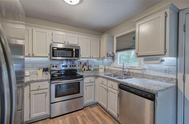 80 Broadlands Dr, White, GA 30184 - kitchen featuring stainless steel appliances, backsplash, light wood-style floors, light stone counters, and a textured ceiling