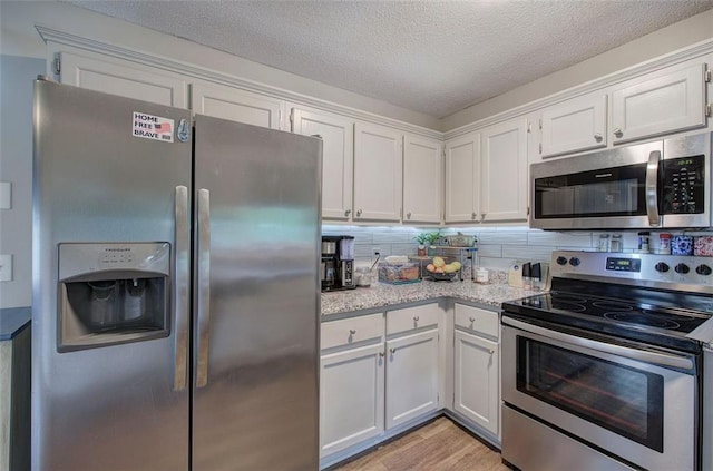 80 Broadlands Dr, White, GA 30184 - kitchen with appliances with stainless steel finishes, light wood finished floors, white cabinets, a textured ceiling, and decorative backsplash