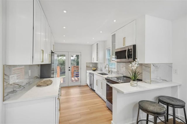 kitchen with decorative backsplash, white cabinetry, sink, and appliances with stainless steel finishes