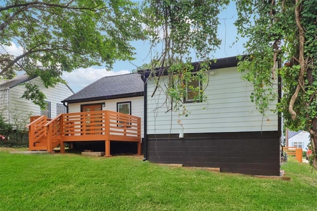 rear view of property featuring a lawn and a wooden deck