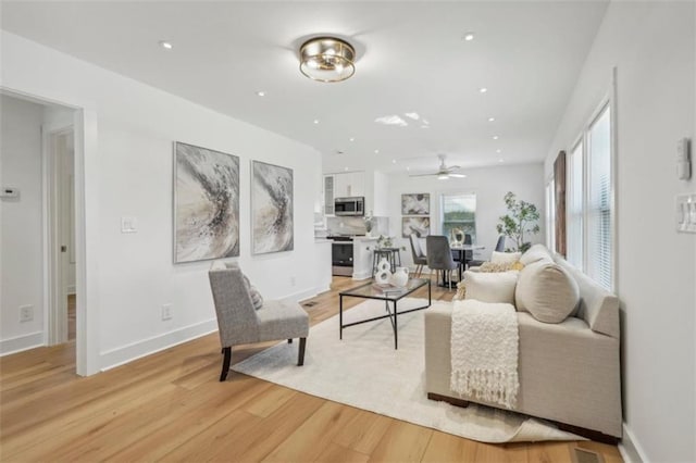 living room with ceiling fan and light wood-type flooring