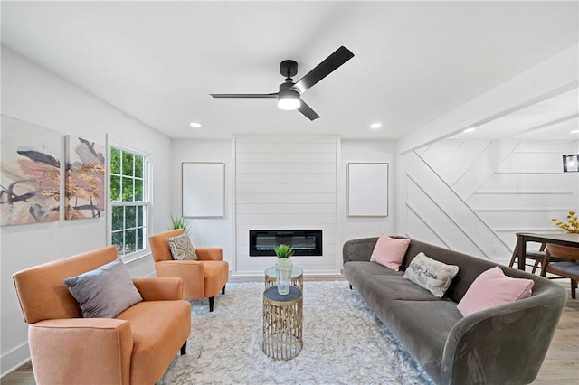 living room featuring a large fireplace, light hardwood / wood-style floors, and ceiling fan